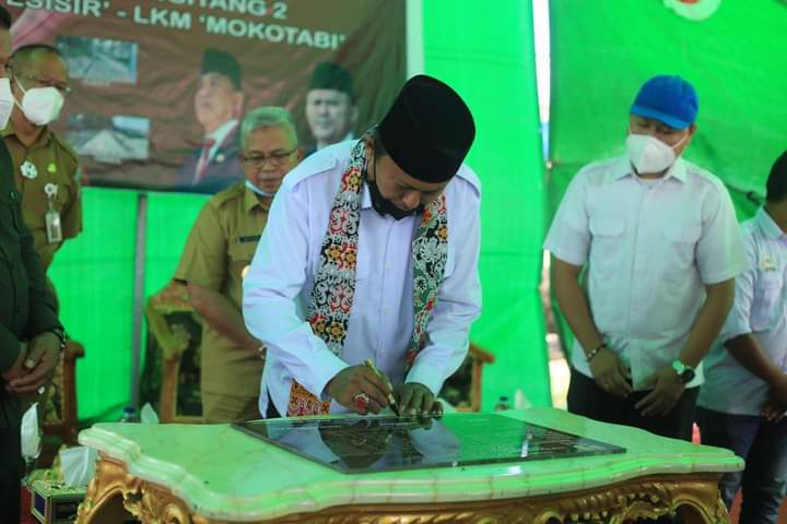 APRESIASI : Didampingi Bupati Depri Pontoh, Anggota DPR-RI Herson Mayulu menandatangani prasasti peresmian KOTAKU. (foto/ist)