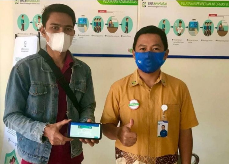 Didampingi petugas BPJS, Taufik Pratama Putra menunjukkan aplikasi Mobile JKN di Handphone miliknya. (foto/ist)
